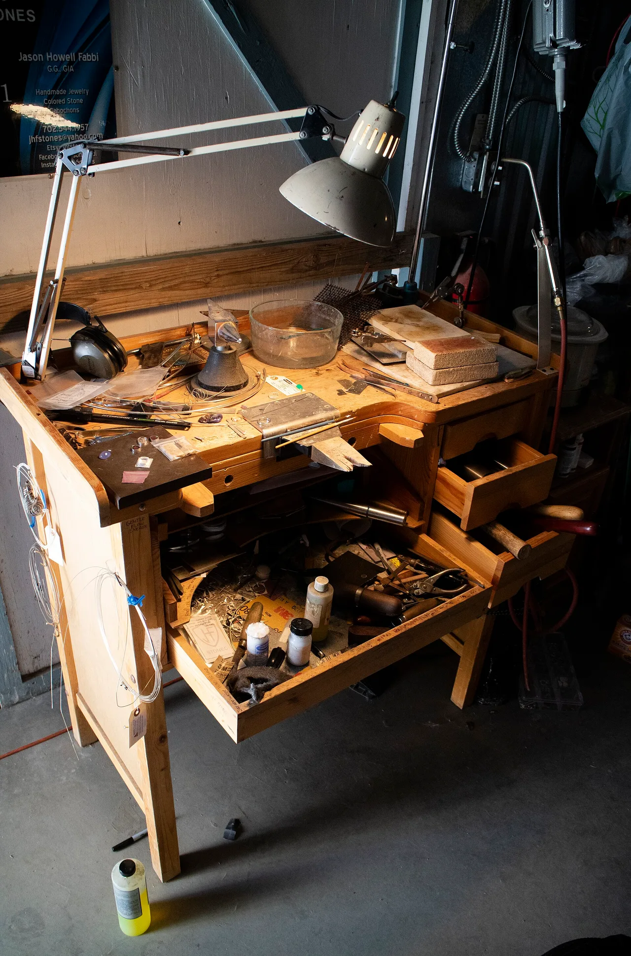 A jeweler's workbench with lighting, torch, tools, and flexible-shaft equipment