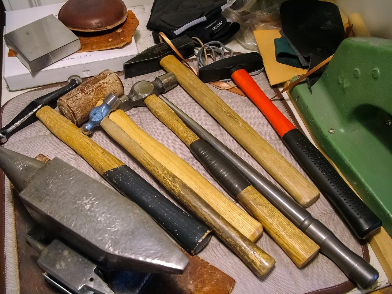 Jewelry-forming tools including hammers, anvils, a mandrel, blocks, and a sandbag