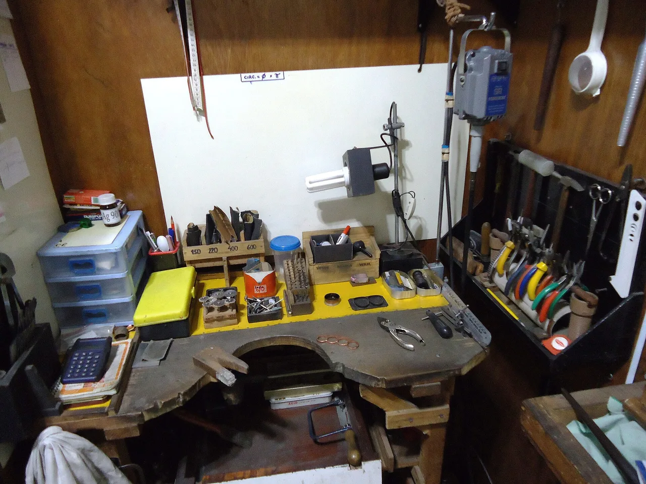 Silversmithing bench with hand tools, task lighting, storage, and a bench-pin area