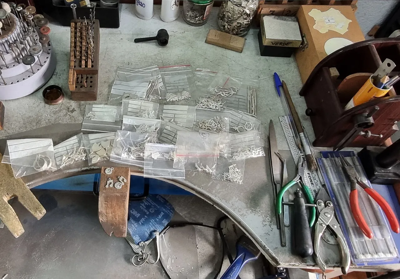 A working jewelry bench holding cast silver pieces and hand tools